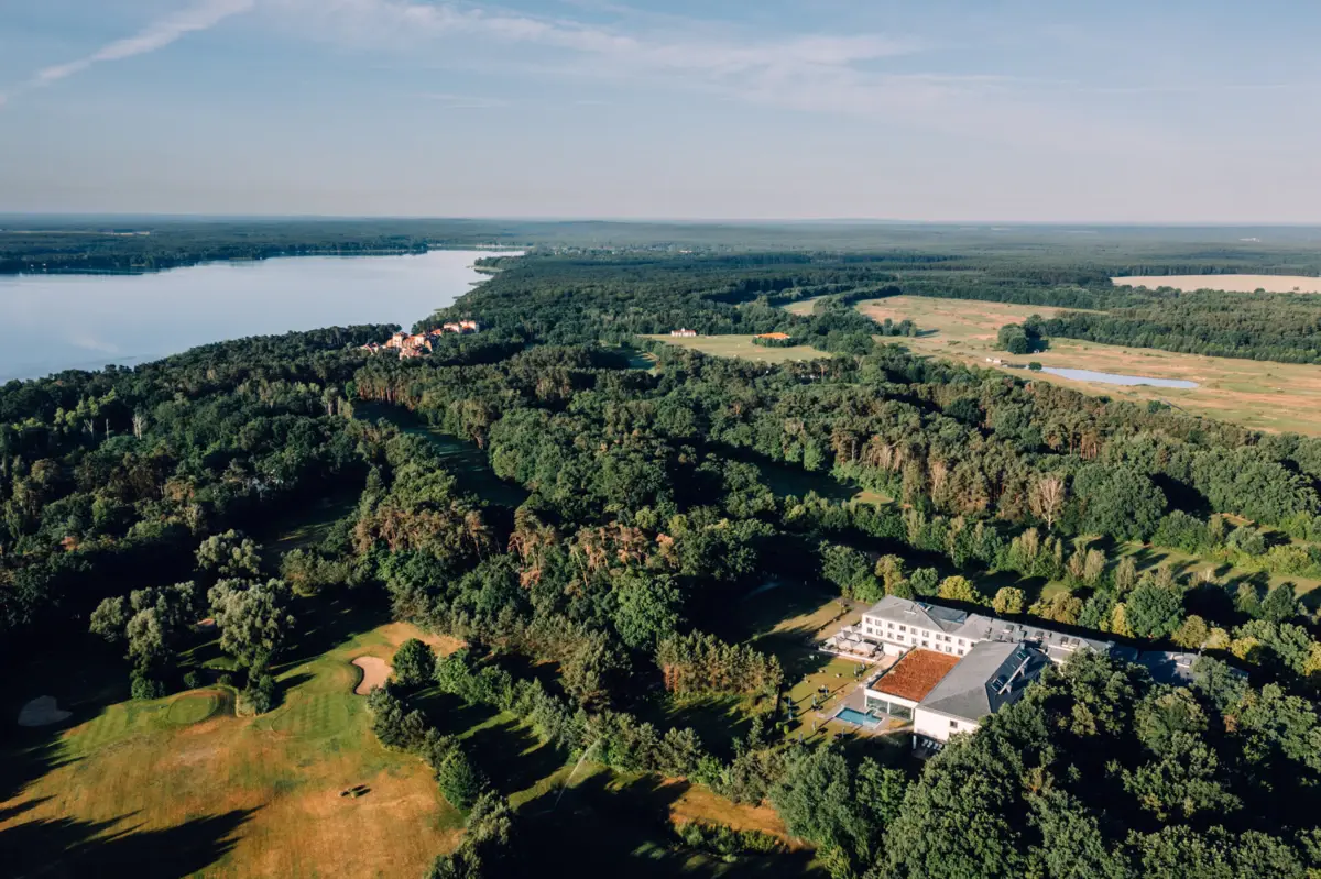 A large building surrounded by trees and a body of water.