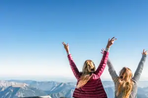 Two women with their arms raised, looking up to the sky.