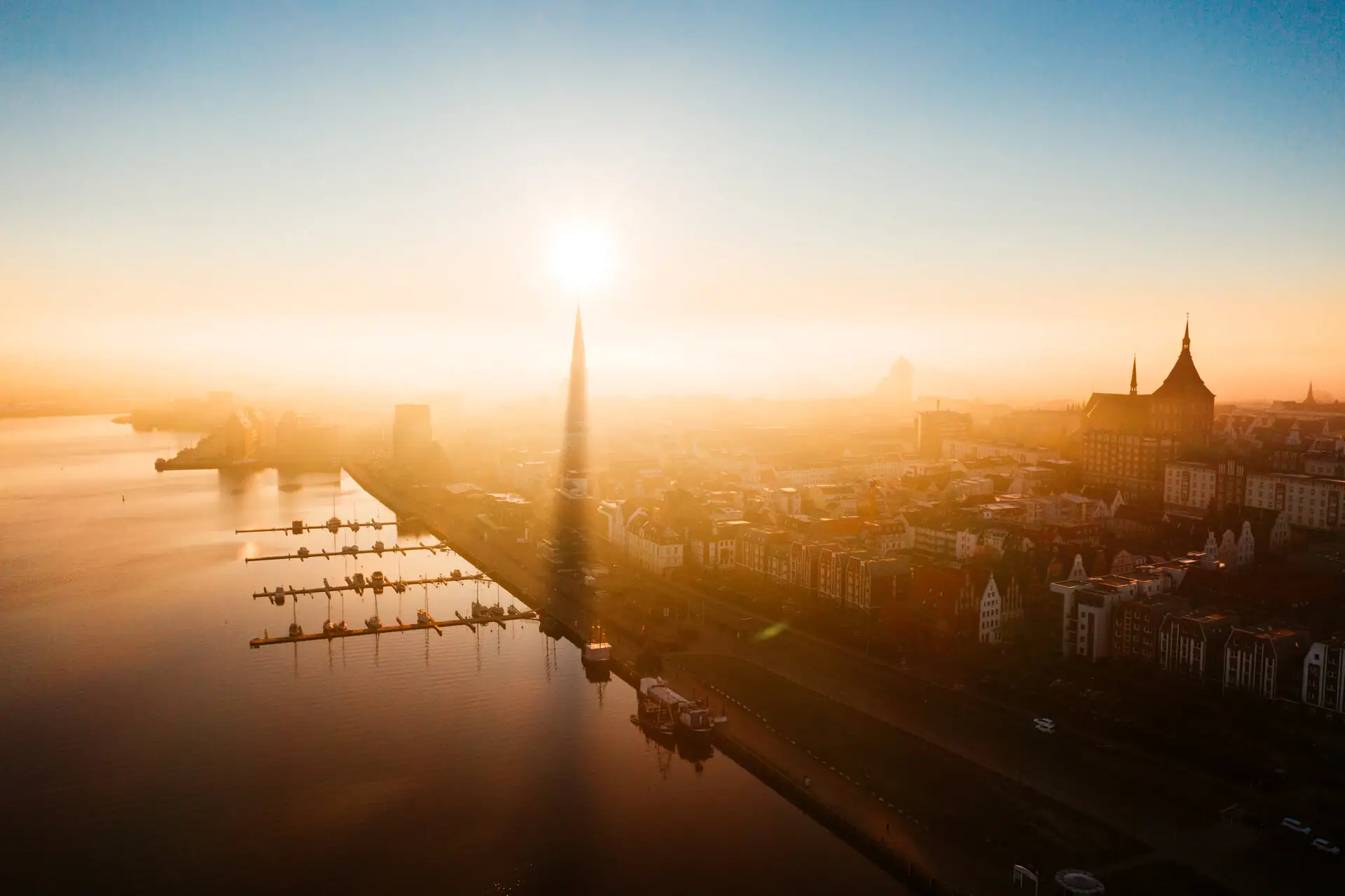 A town with a body of water and a high tower at dawn.