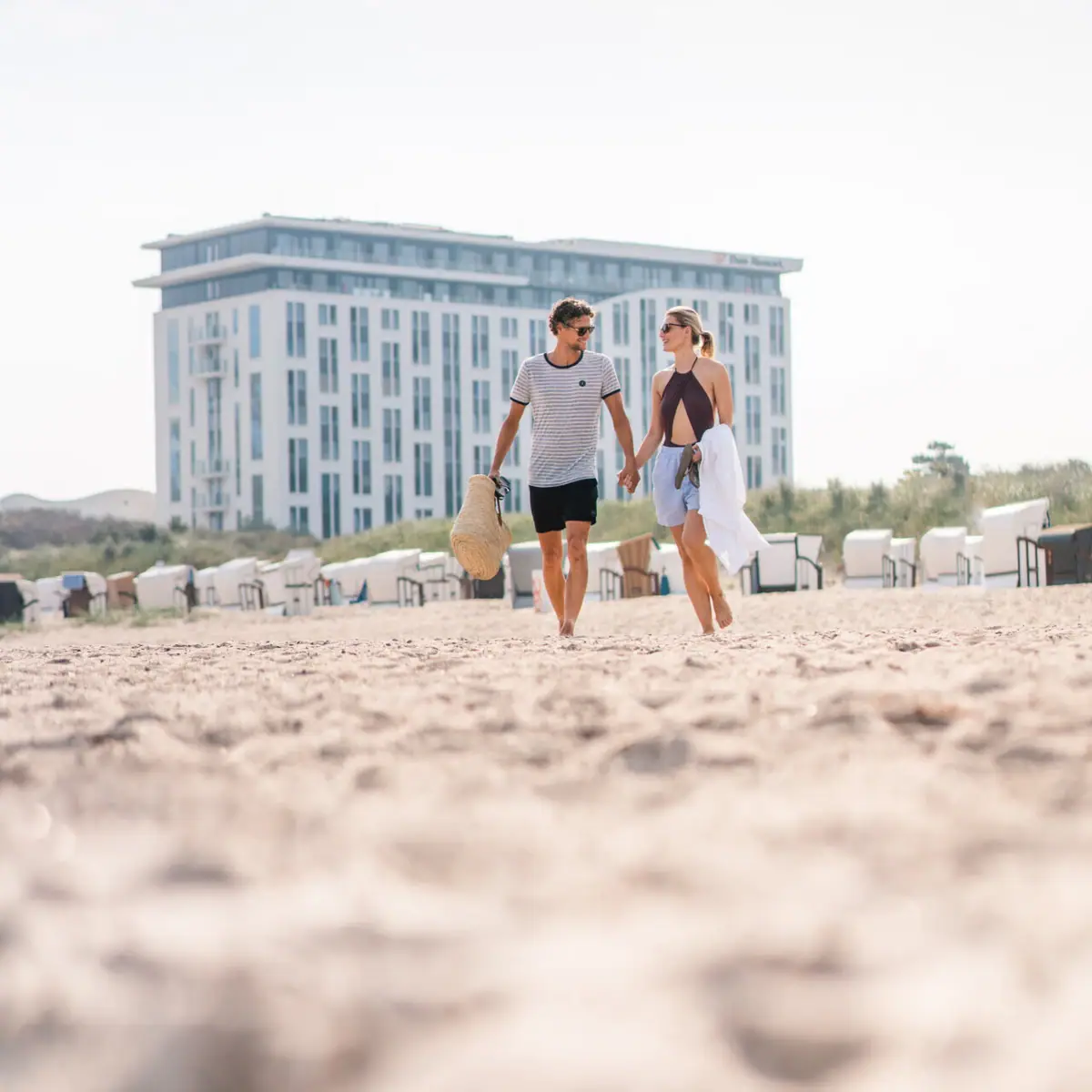 A man and a woman holding hands on the beach.