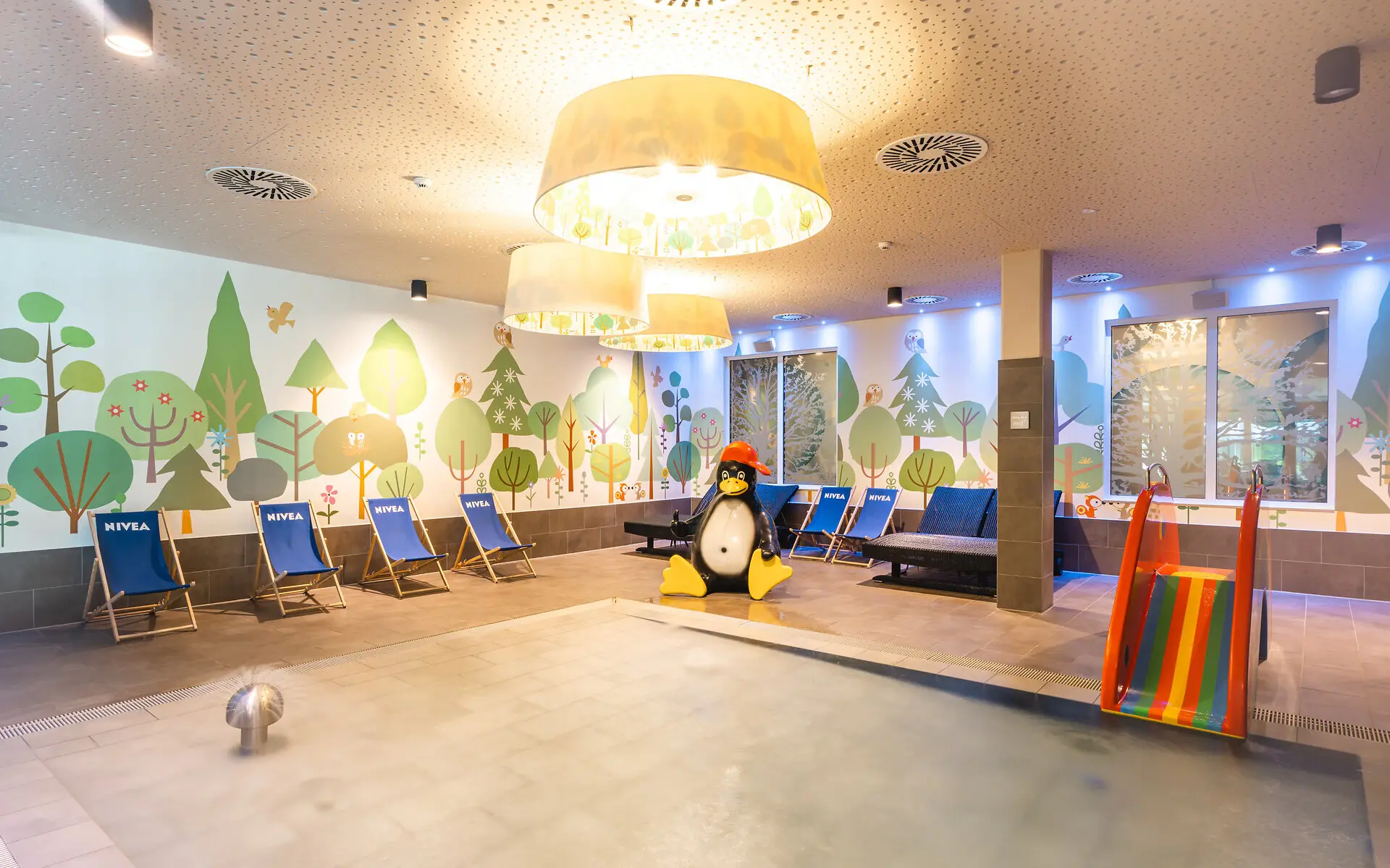 Indoor pool area with chairs and a decorative penguin figure.