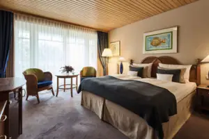 Bedroom with bed and chairs, equipped with pillows and bed linen.