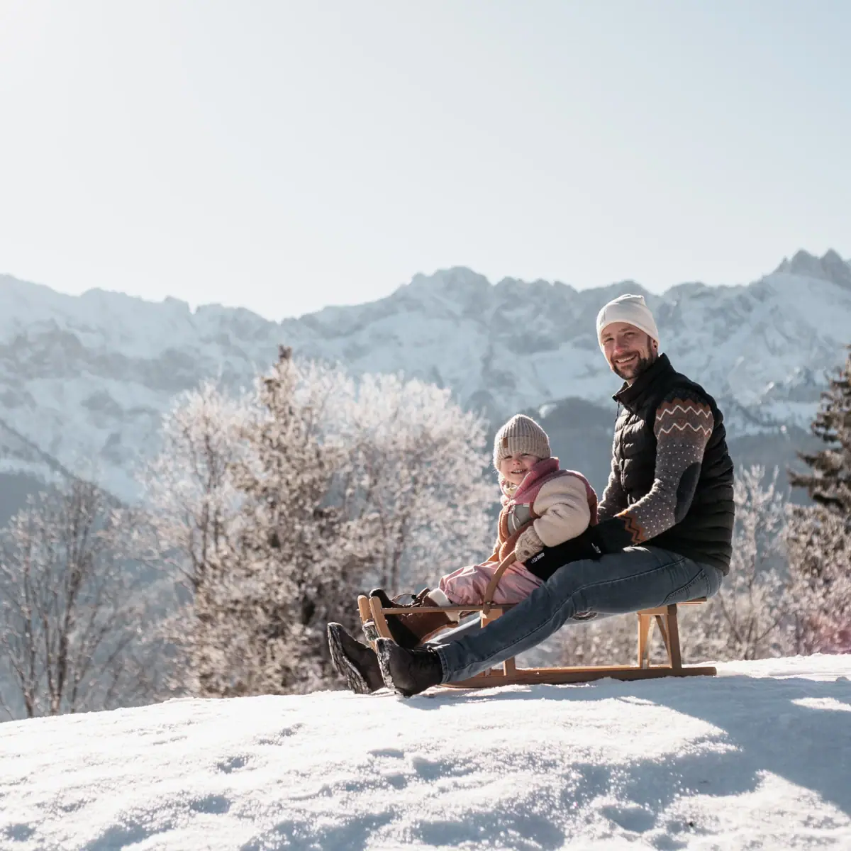 A father and his daughter on a sledge during a family holiday in Garmisch-Partenkirchen.