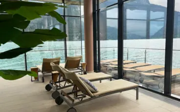 Lounge chair in a room with a large window through which you can see the sea.