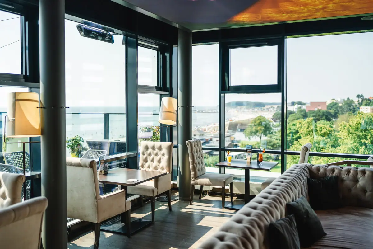 The aja Rooftop Bar in Grömitz with large windows, cosy seating areas and delicious cocktails on one table.