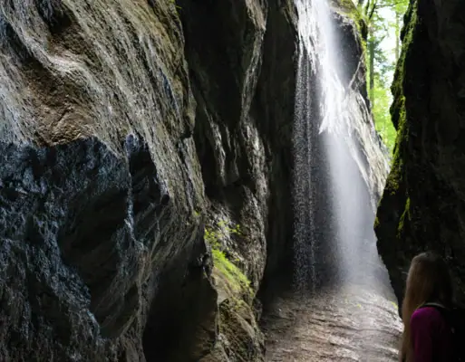 A woman stands in a cave with a waterfall.