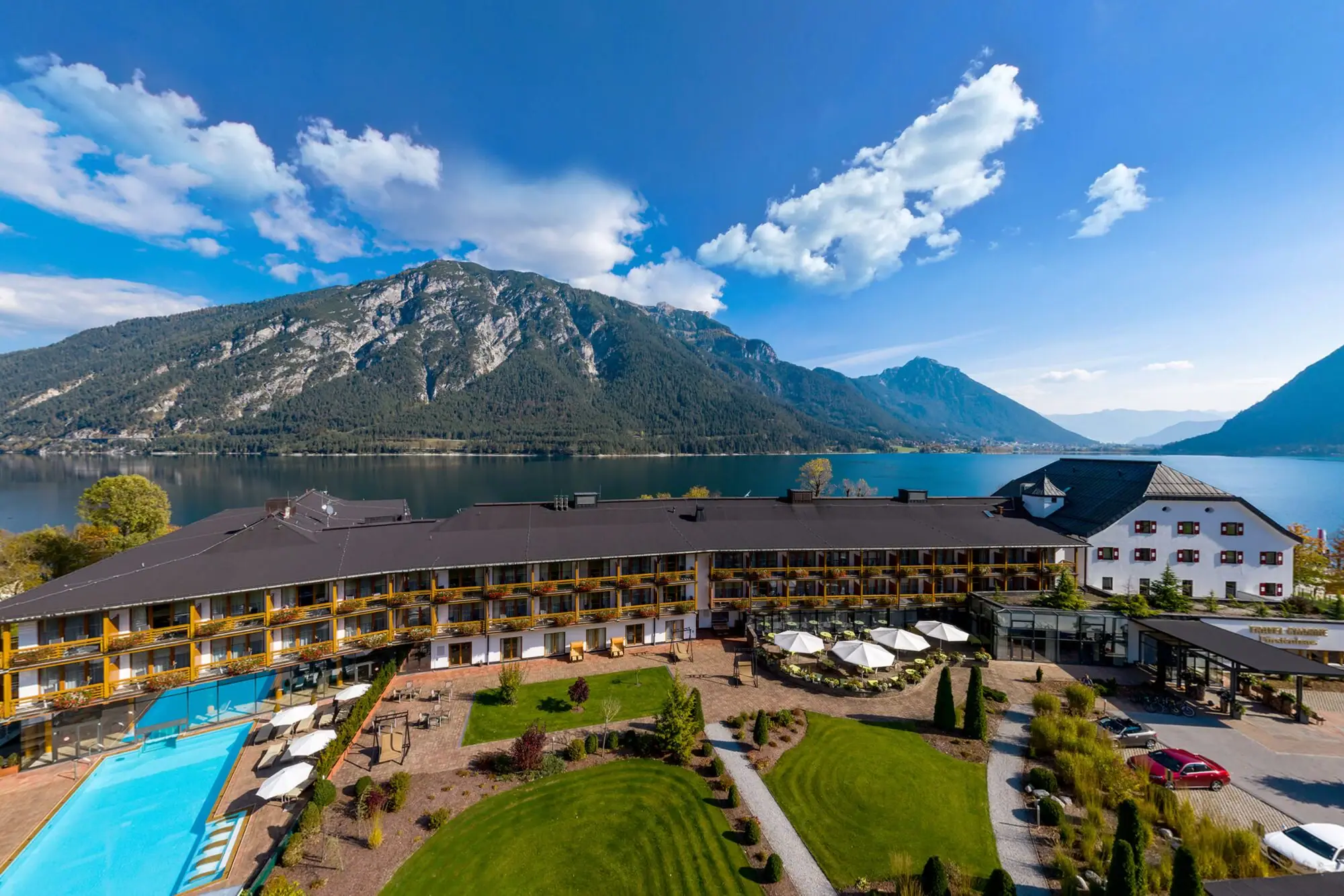 A building with a pool and lawns by a lake.