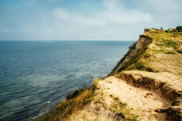 Cliff with a view of a body of water in the background.