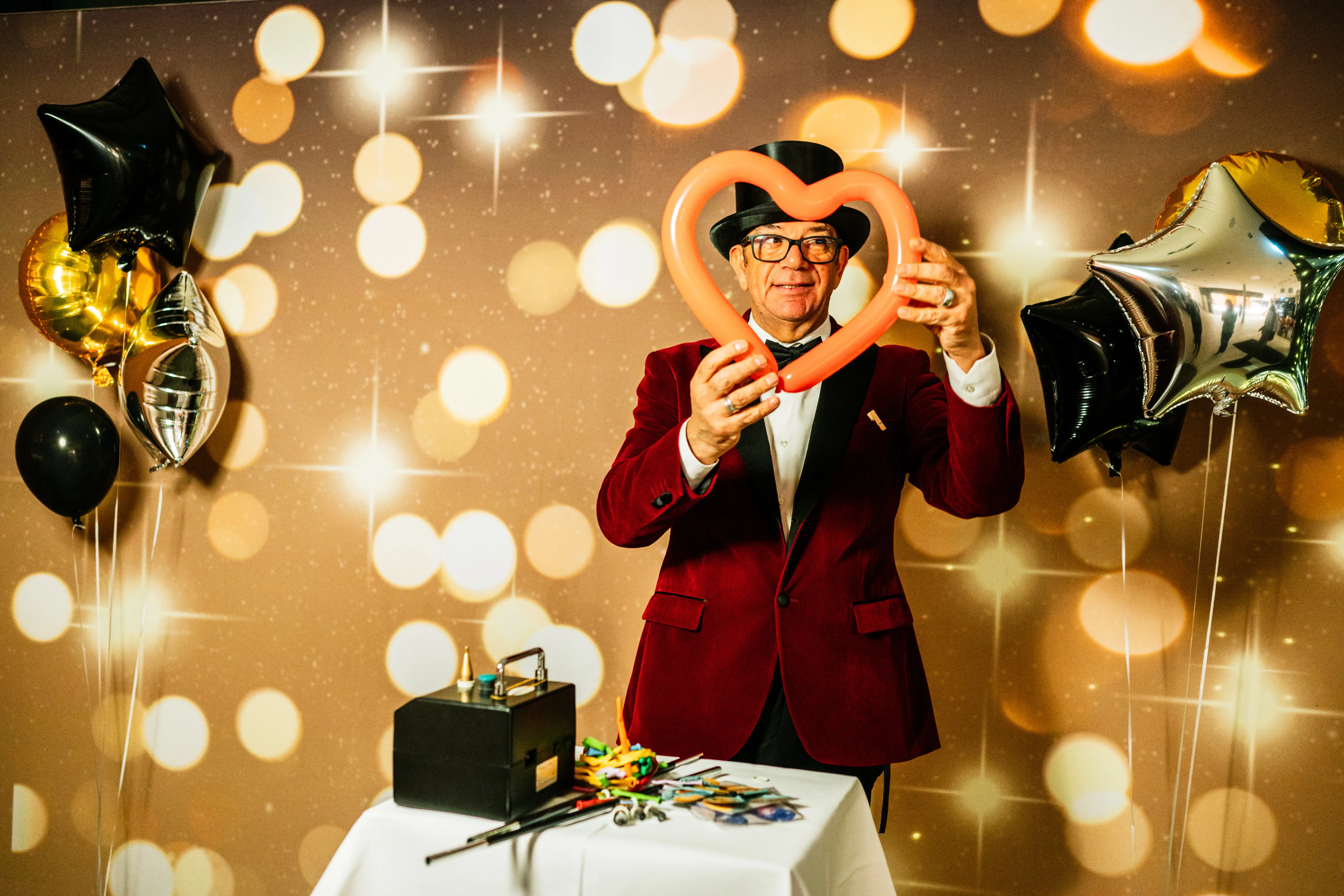A man in a red suit makes figures out of long balloons