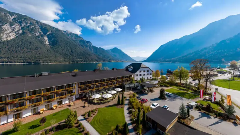 The aja Fürstenhaus am Achensee is located directly on Lake Achensee, surrounded by trees and mountains.