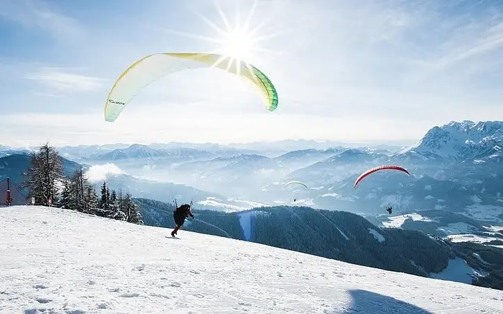 Group of people paragliding on a snowy mountain.