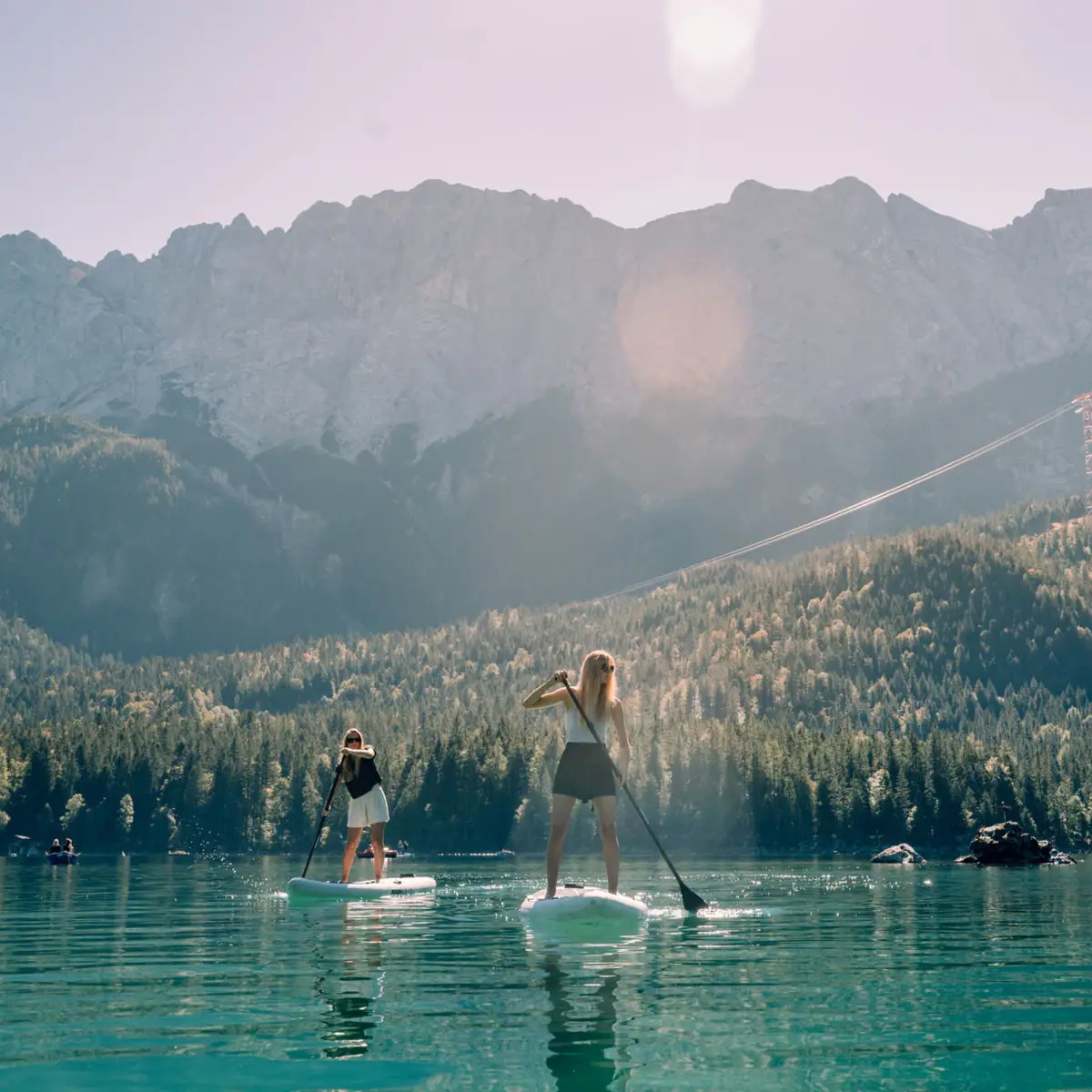 Women on paddleboards on a lake against a mountain backdrop