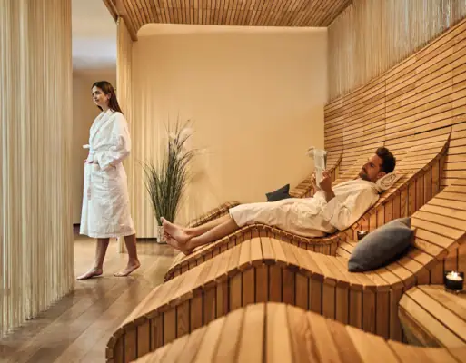 Werfenweng wellness area A man and a woman in a room with wooden benches.