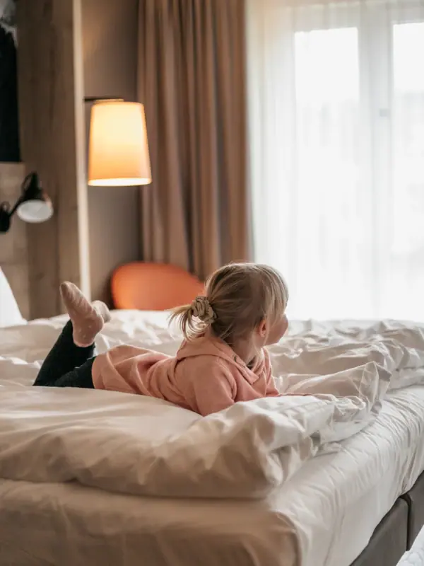A child is lying on a bed in an aja family hotel in Bavaria.