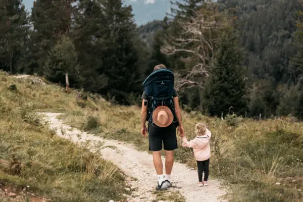 A man and a child are walking along a forest path.