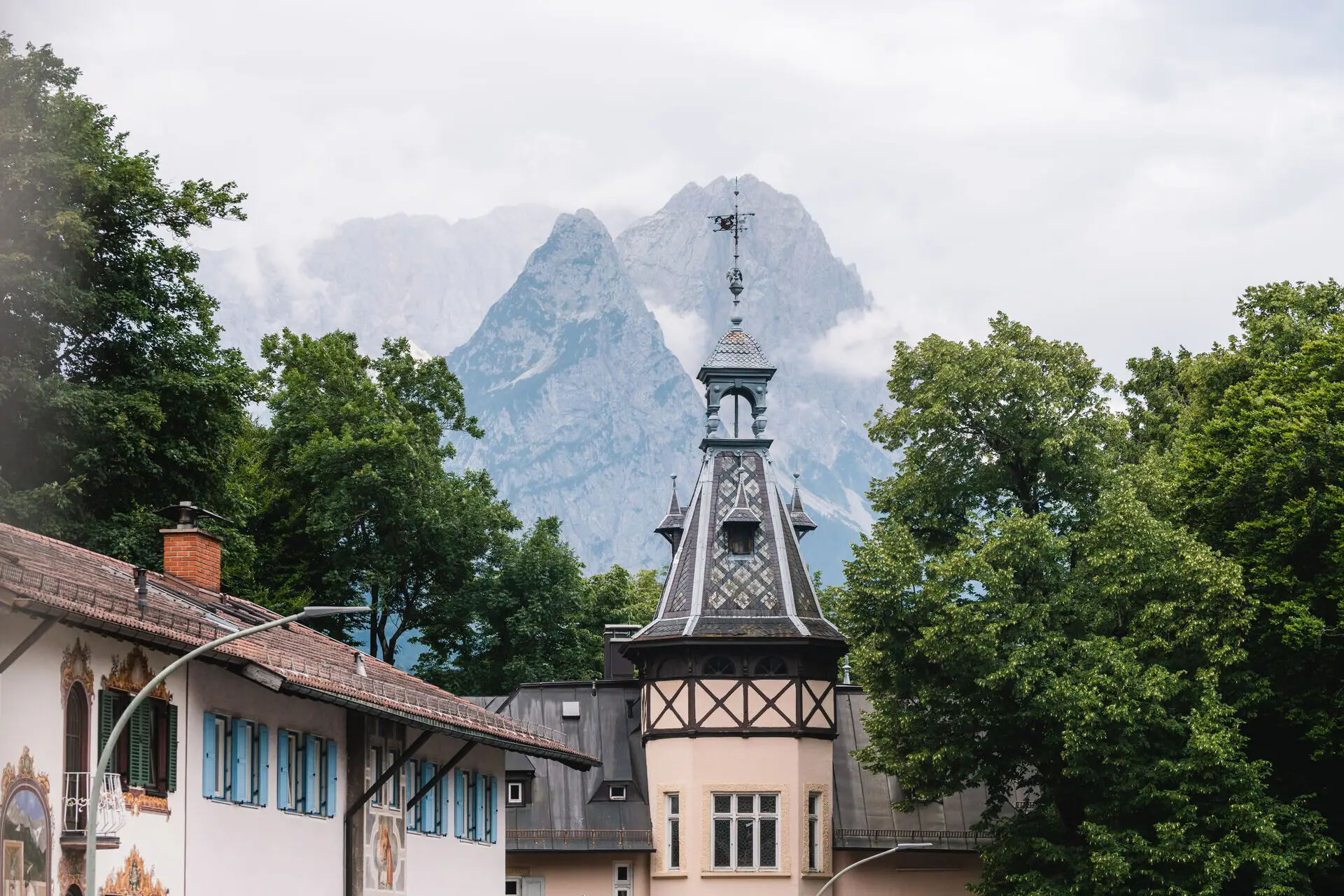 A building with a tower and trees in front of mountains.