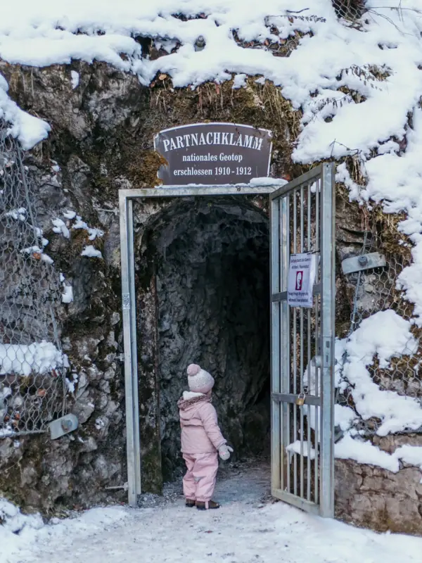A small child is standing at the entrance to the Partnach Gorge whilst on a family holiday in Bavaria.