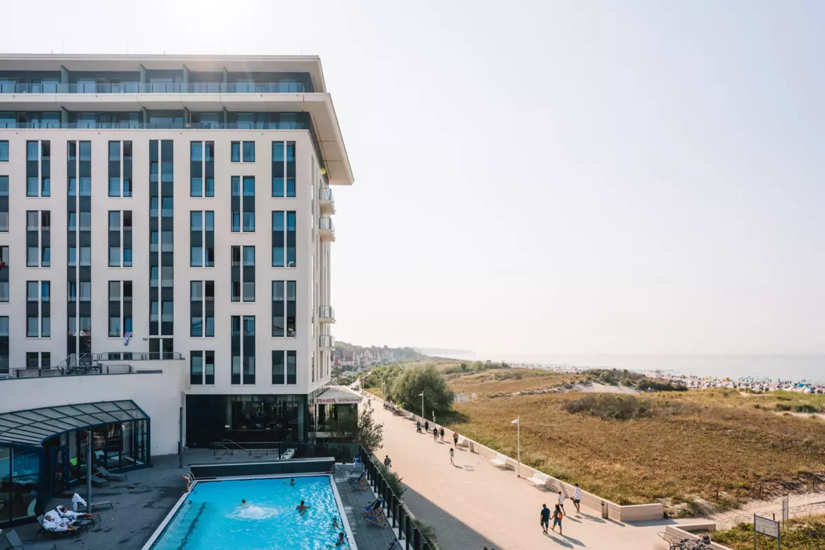 The aja Warnemünde, with its pool and adjacent dunes, and the beach in the background.