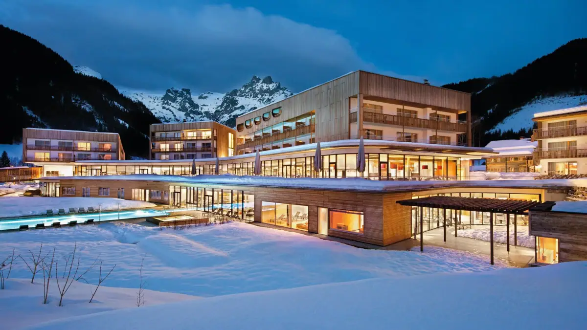 An illuminated hotel building on snow-covered ground.