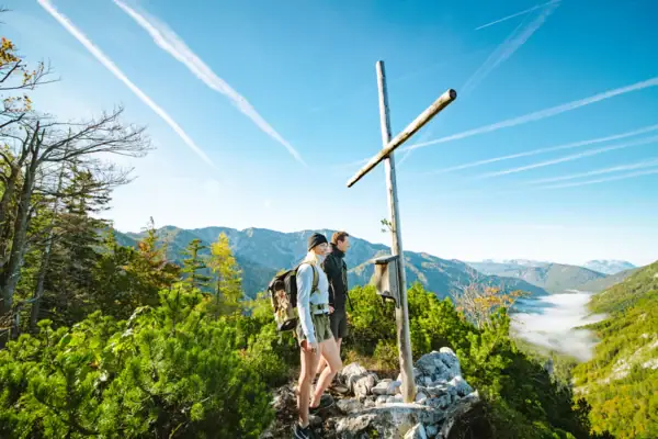 Summit cross Two people are standing on a rock with a cross on a mountain.