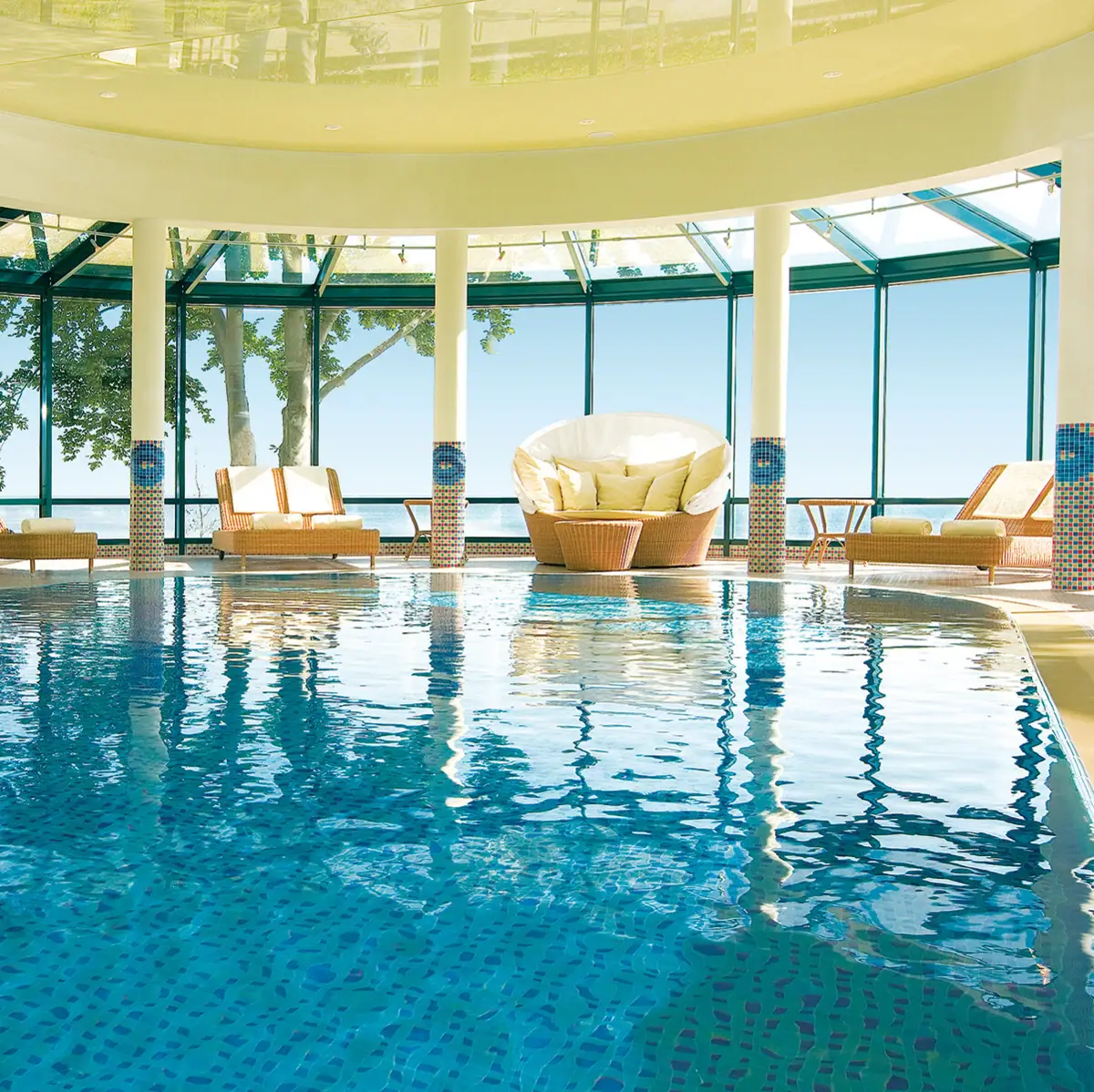 An indoor pool with chairs and a large ceiling.