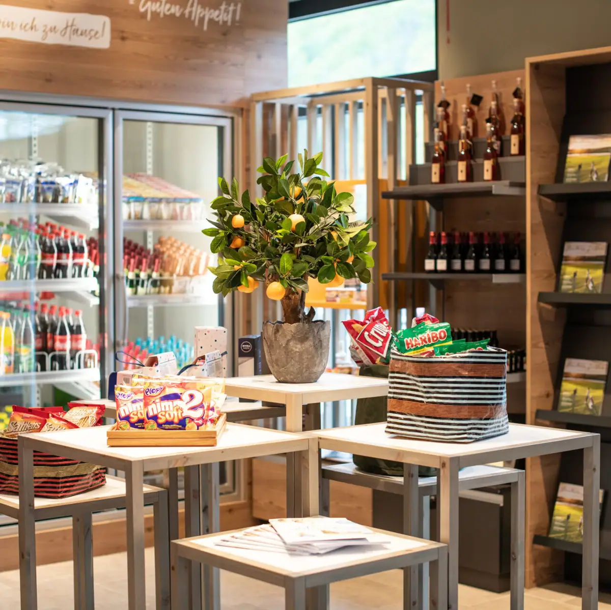 A table with food and a plant on it in a shop with drinks and snacks.