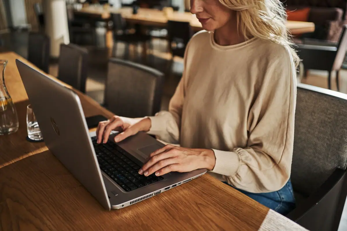 Laptop A woman is sitting at a table using a laptop.
