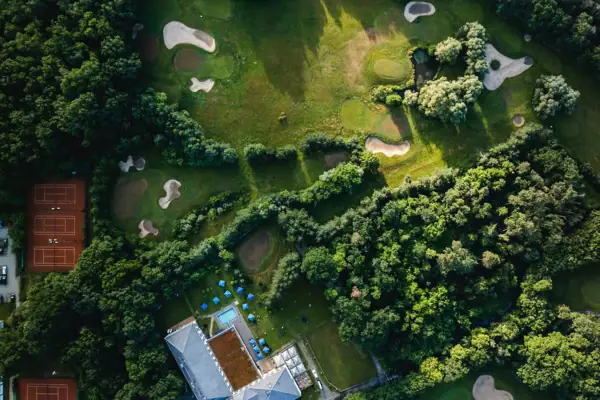 Aerial view of a golf course with trees and a water hazard.