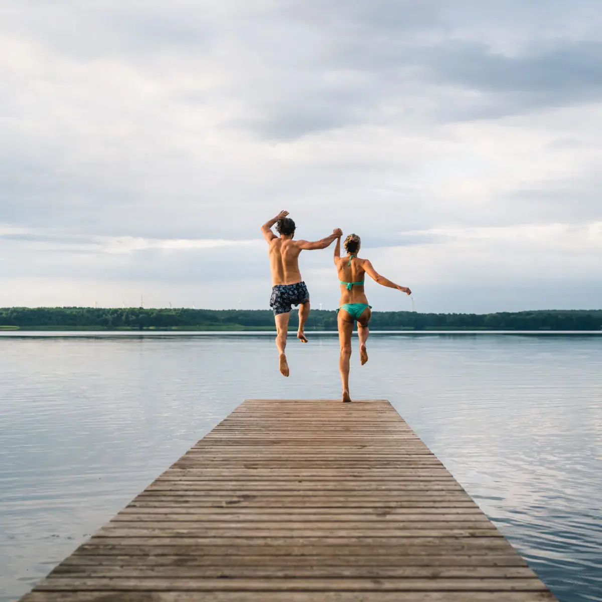 A man and a woman jump into the water.