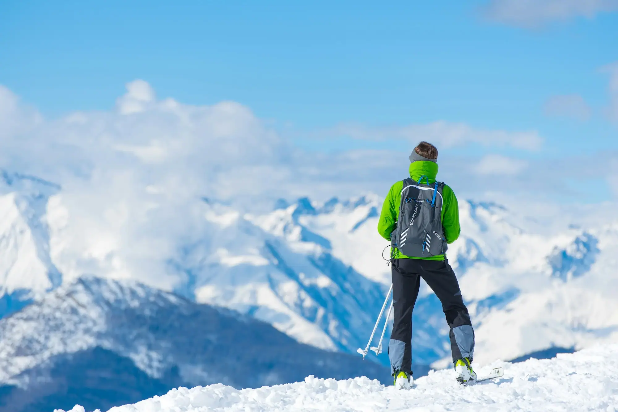 Person on skis looks at snow-covered mountains.