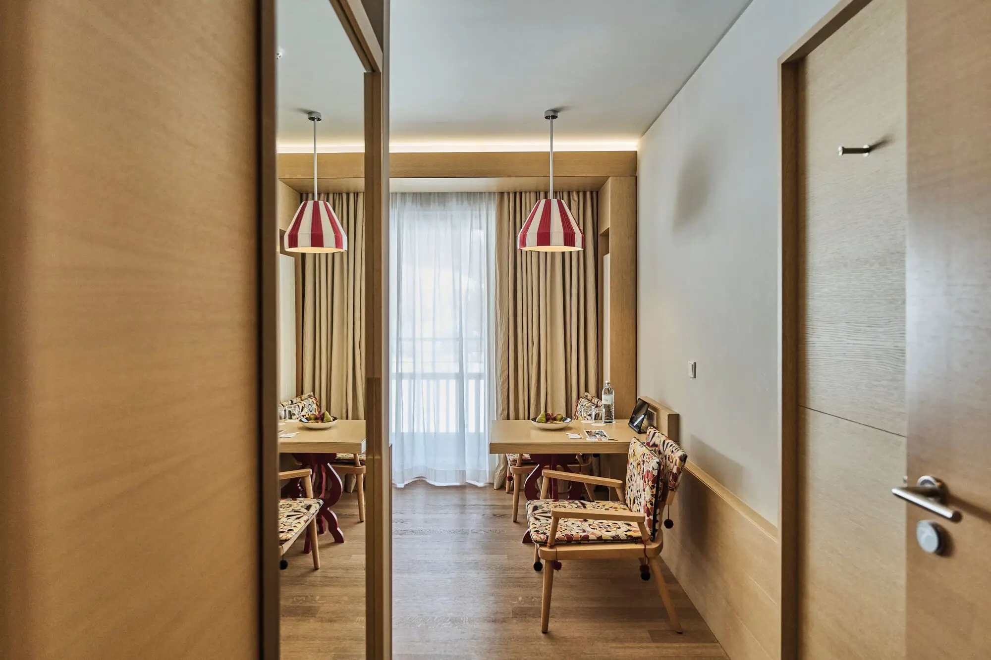 Interior with table and chairs, complemented by mirror and wooden floor.