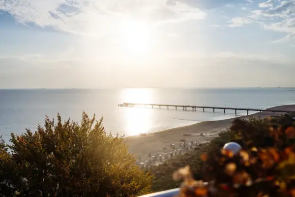 A pier on the beach under a cloudy sky.
