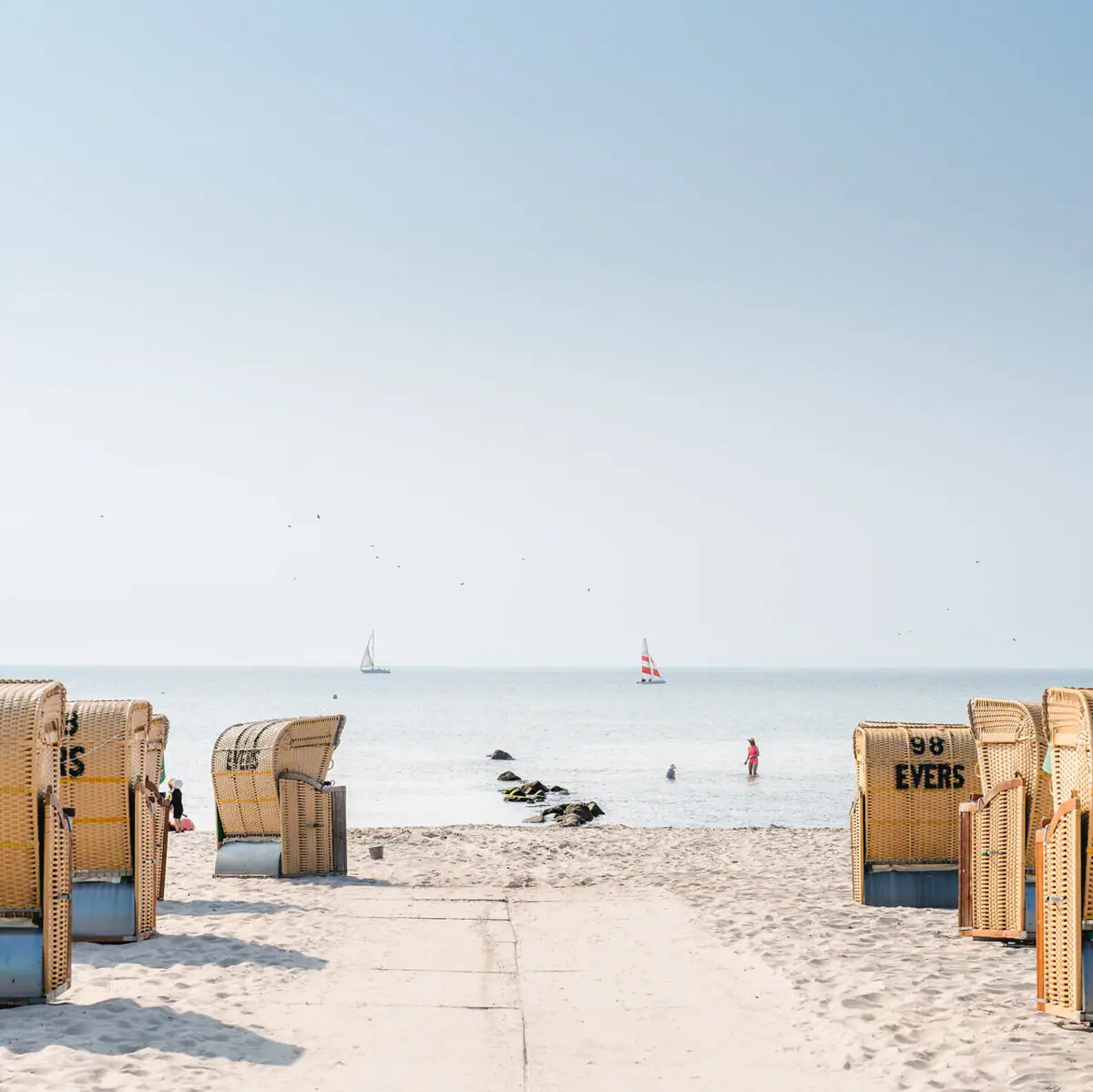 A beach with many baskets and a body of water.
