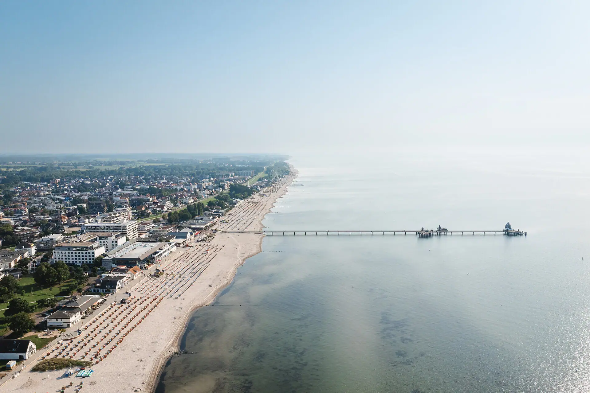 Beach with a pier and buildings in the background.