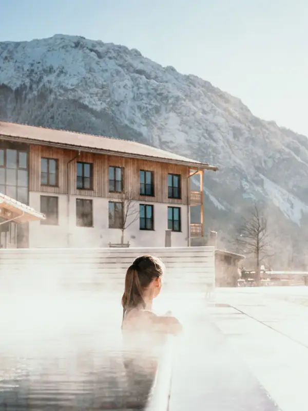 A woman in a steaming outdoor pool.