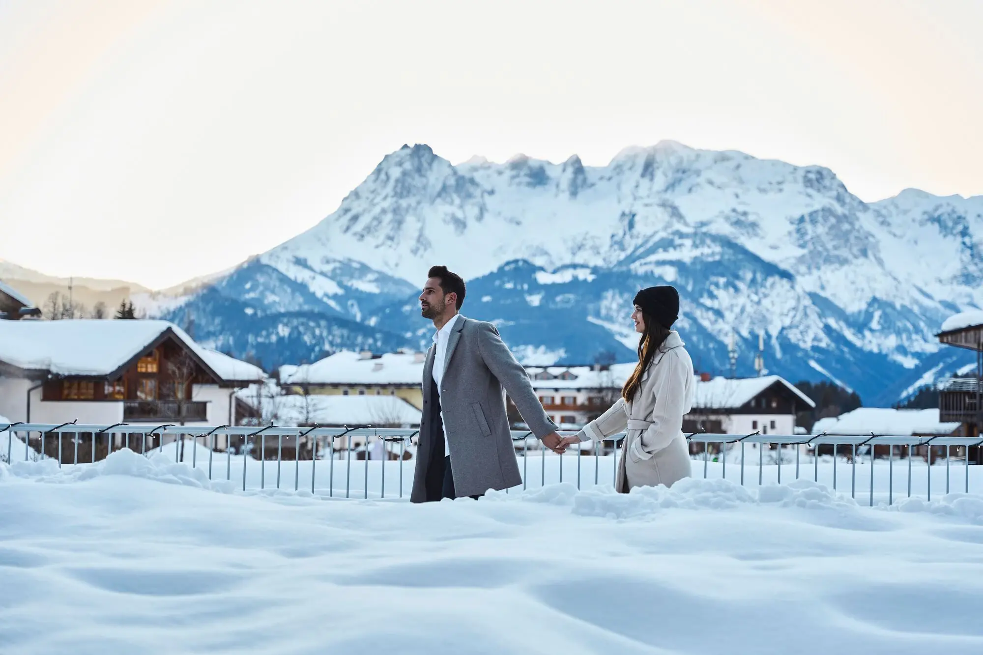 A man and a woman hold hands in the snow.