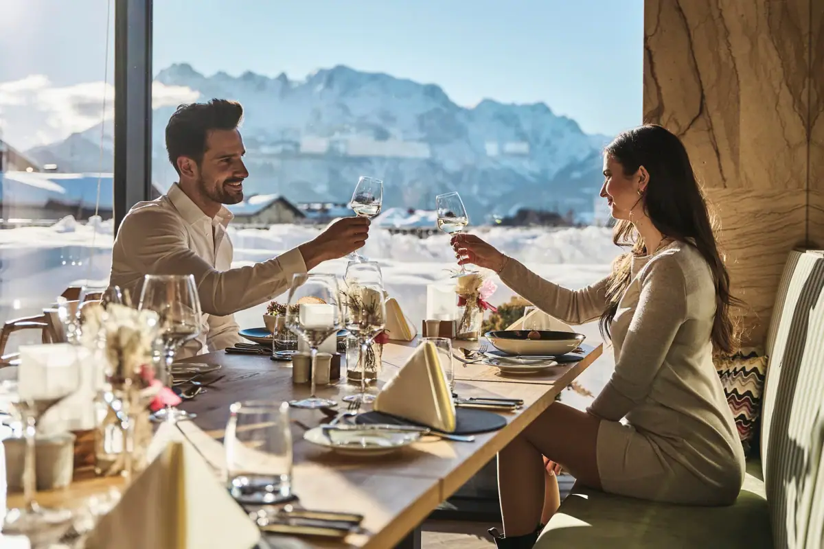 A man and a woman are sitting at a table with glasses of wine.