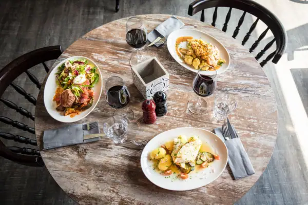 A table with plates full of food and wine glasses.