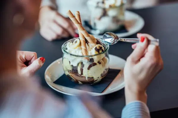 Ice cream sundae A person is eating dessert with a spoon.