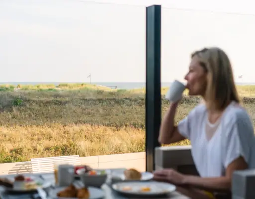 A woman is sitting at a table with a cup of coffee.