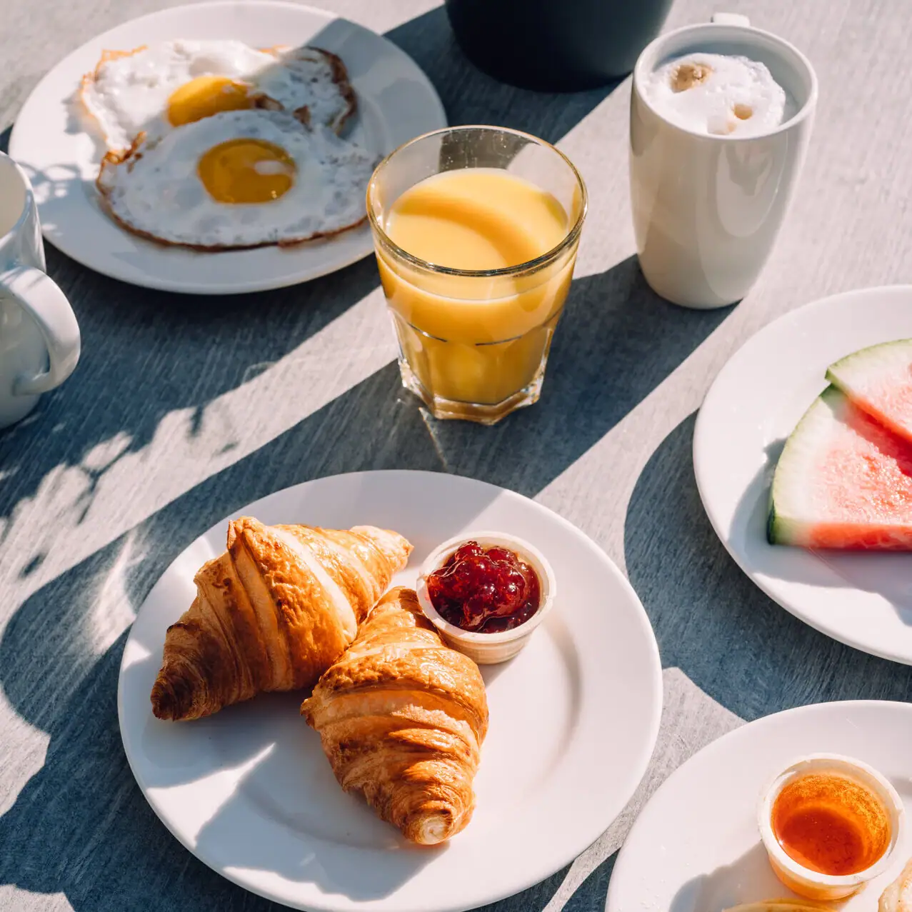 Croissants A table with plates full of food and drinks.