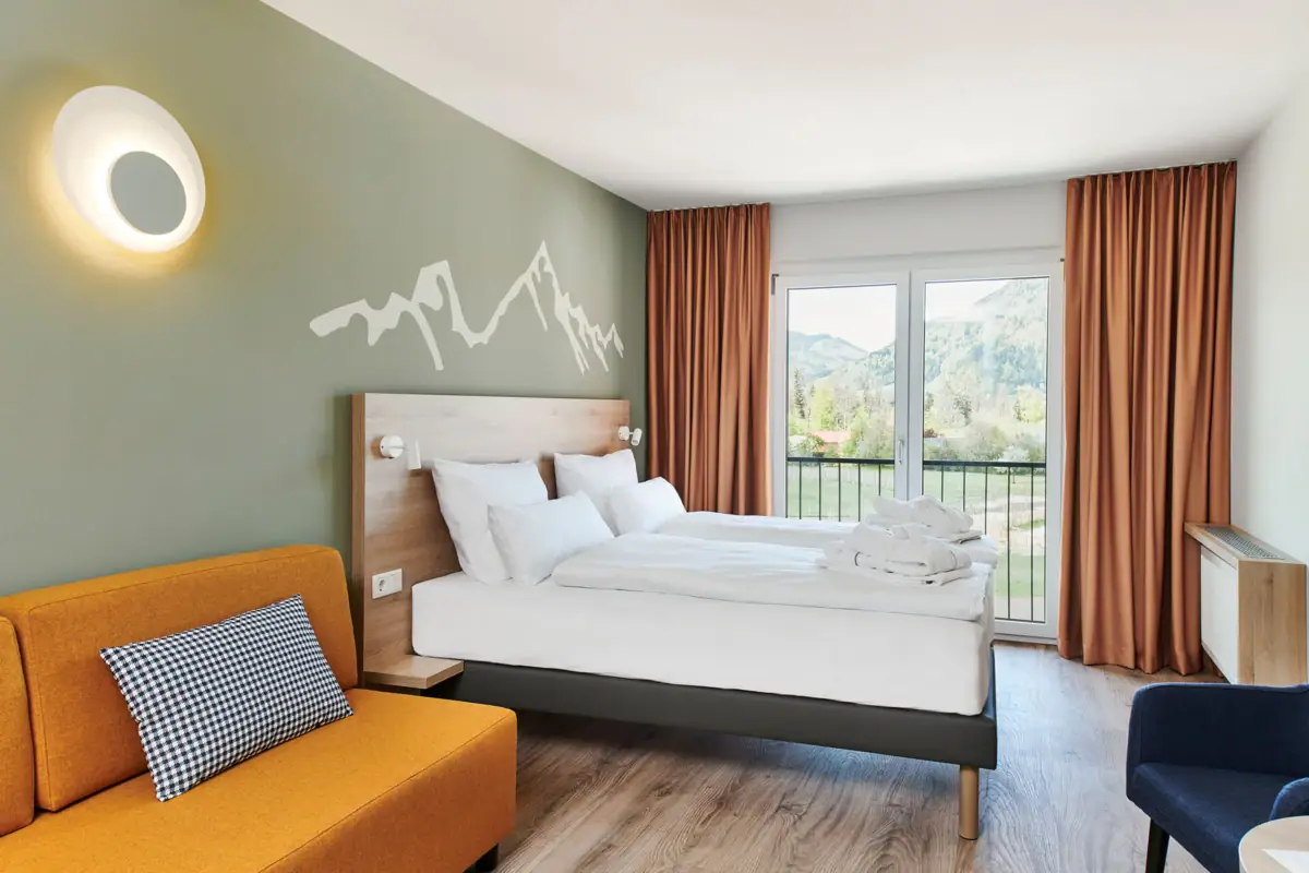 Room with French balcony at the aja Ruhpolding A room with two beds and a sofa.