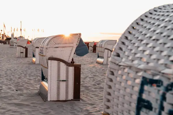 A group of white wicker chairs on the beach.