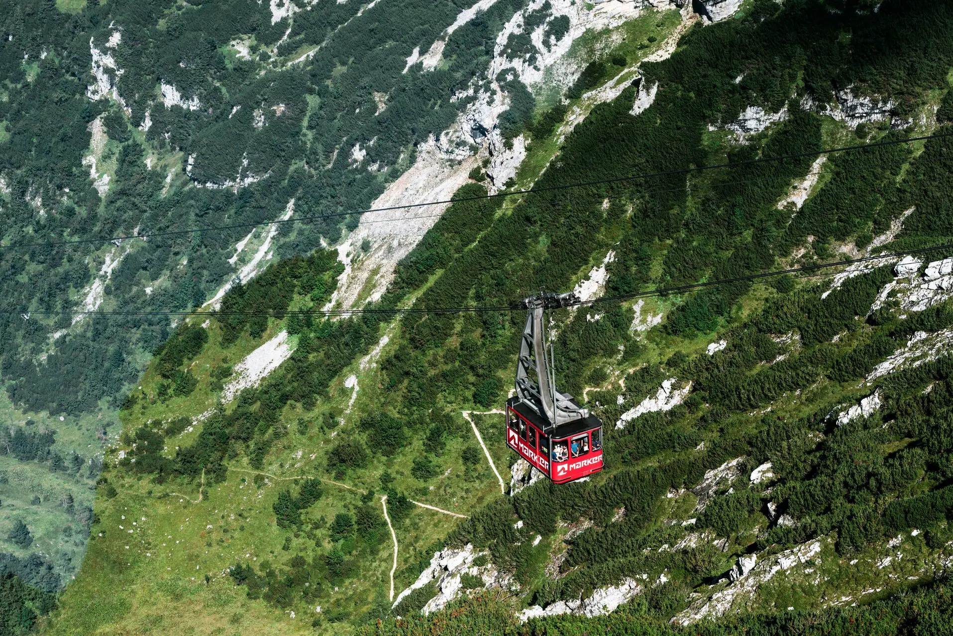 A red cable car gondola in the mountains.