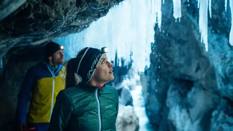 A woman looks up at icicles on the ceiling in a cave.