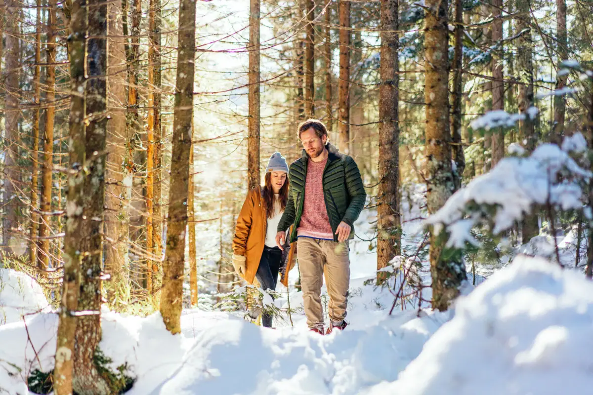 A man and a woman go for a walk in the snow.