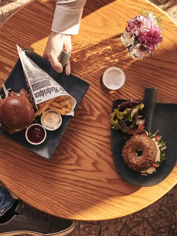 A person holds a plate of food at a table.