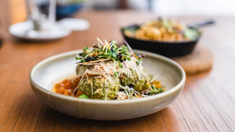 A bowl of salad with garnish on a table.