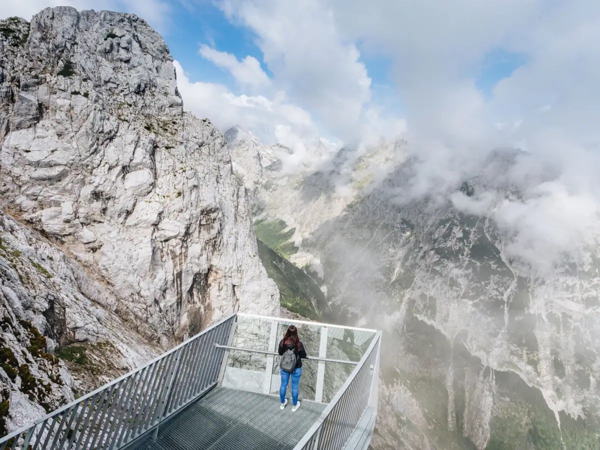 AlpspiX A woman stands on a bridge over a mountain.