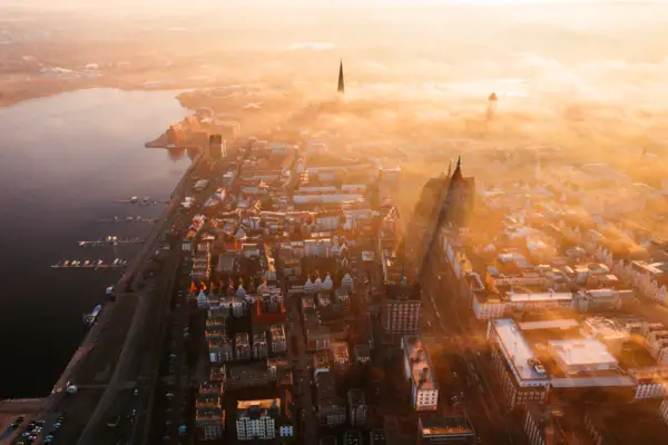 Bird's eye view of a foggy city with a body of water in the foreground.
